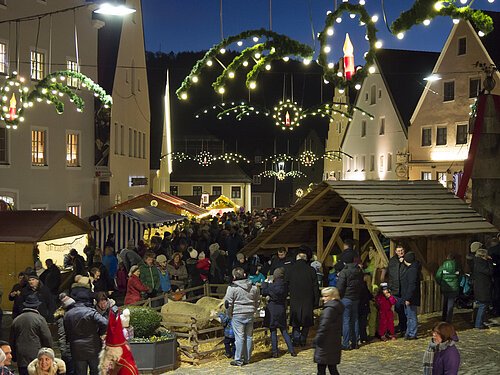 Weihnachtsmarkt Weihnachtsmarkt mit Ständen, Menschen und festlicher Beleuchtung in einer Altstadt bei Nacht.